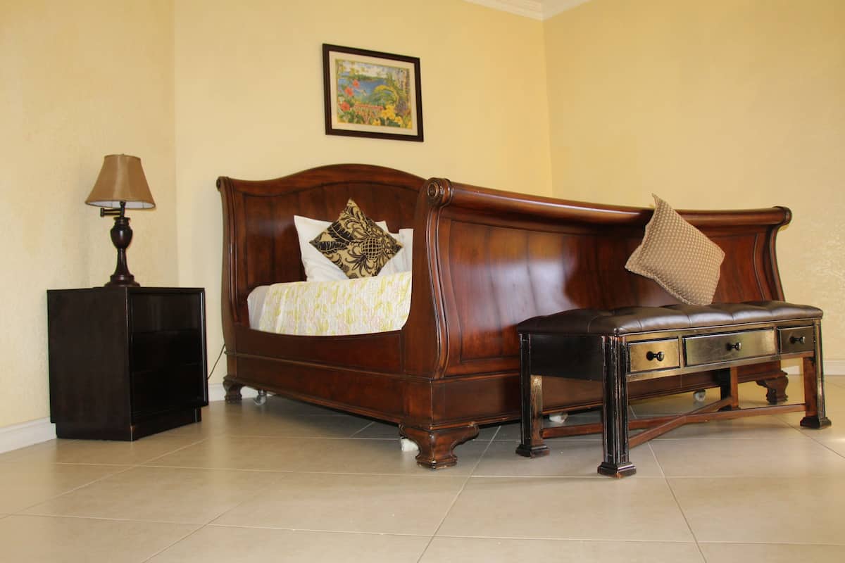 A bedroom with a wooden bed, a bedside table, a lamp, and a framed picture on the wall.