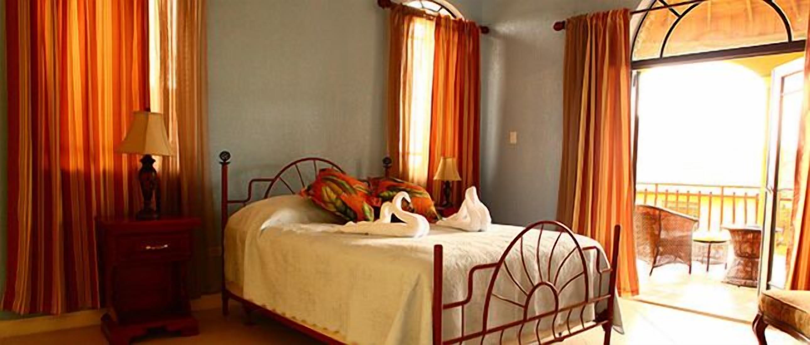 A bedroom with a bed, a nightstand, and a window with curtains.