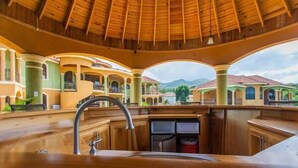 A spacious kitchen with a large sink and a view of a multi-story building with balconies. - Milbrooks Villa and Retreat (Montego Bay)