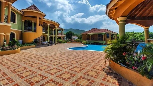 A courtyard with a swimming pool, covered seating areas, and a mountainous backdrop. - Milbrooks Villa and Retreat (Montego Bay)