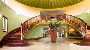 A grand, curved wooden staircase with a central column and a large potted plant at the bottom. - Milbrooks Villa and Retreat (Montego Bay)