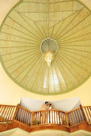 A spacious atrium with a high, wooden ceiling and a central chandelier. A balcony with wooden railings overlooks the interior.