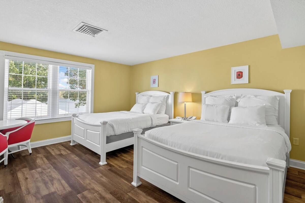 A bedroom with two beds, a desk, and a chair.