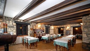 Un restaurante con paredes de piedra, vigas de madera y mesas dispuestas para comer.