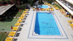 En rektangulär pool med gula solstolar och parasoller på båda sidor.