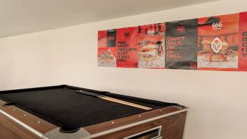 A pool table in a room with a white wall.