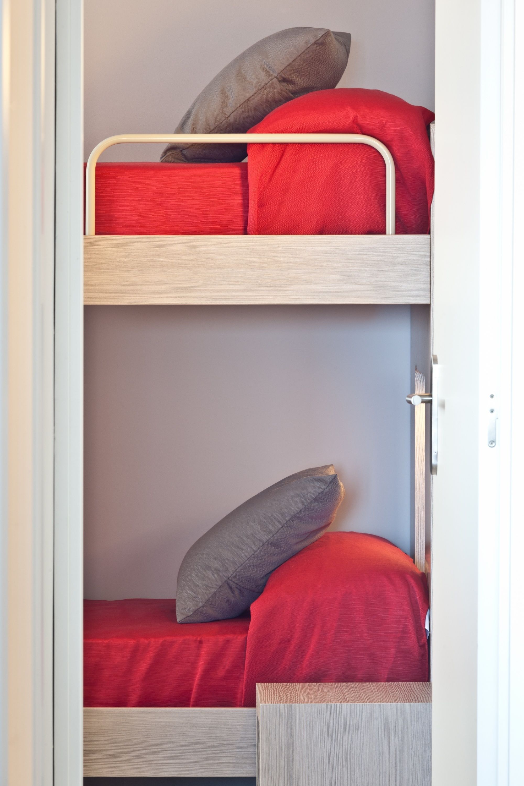 A bunk bed with red bedding and gray pillows.