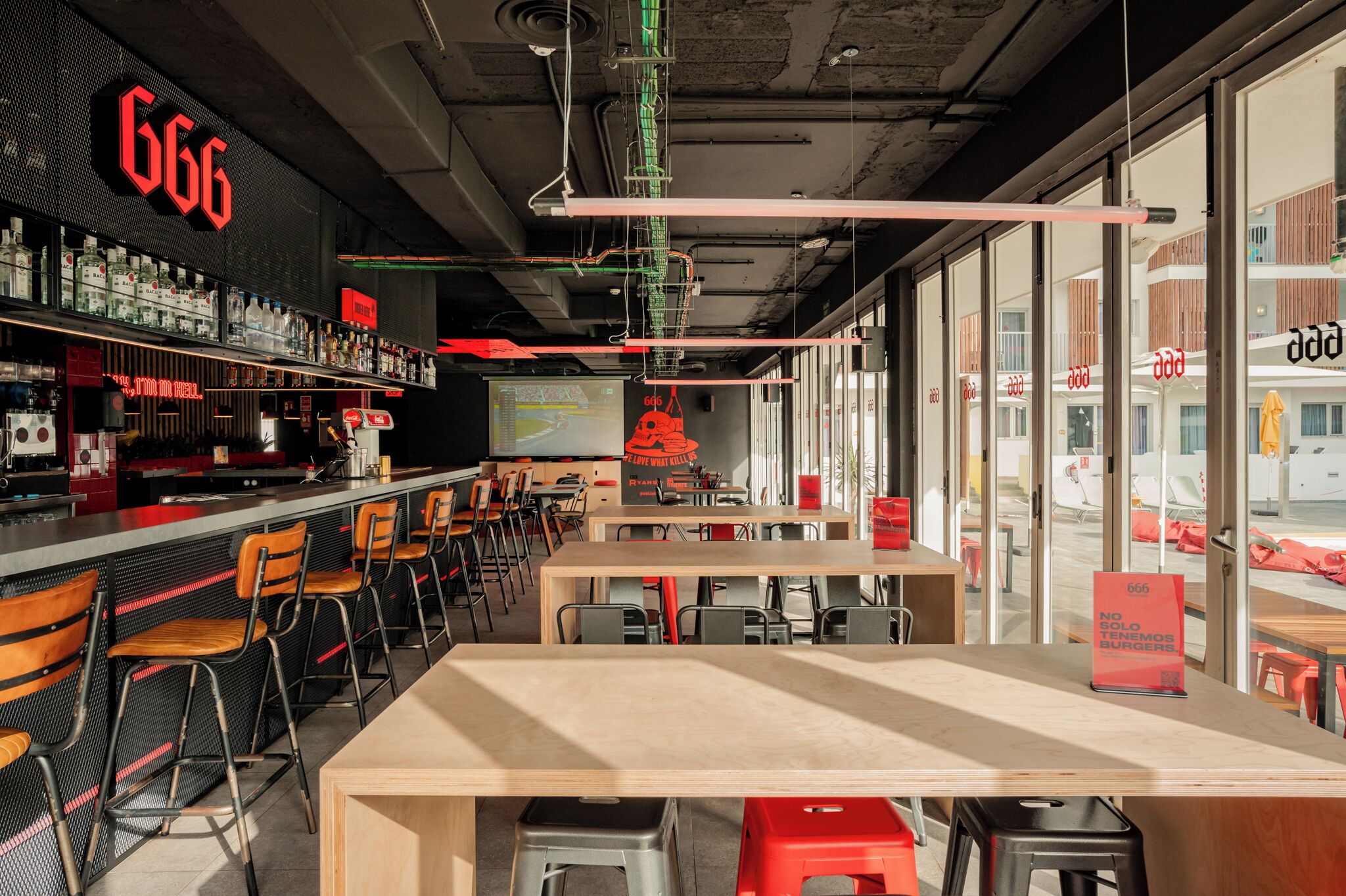 Un restaurant moderne avec un bar, différents types de sièges et une grande fenêtre donnant sur la rue.