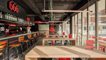 Un restaurant moderne avec un bar, différents types de sièges et une grande fenêtre donnant sur la rue.