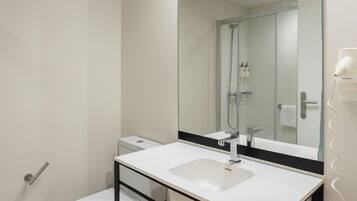 Une salle de bain moderne avec un lavabo blanc, un grand miroir et une douche à parois de verre.