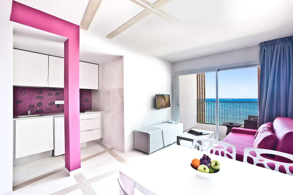 Un apartamento moderno con cocina, comedor y balcón con vistas al mar.