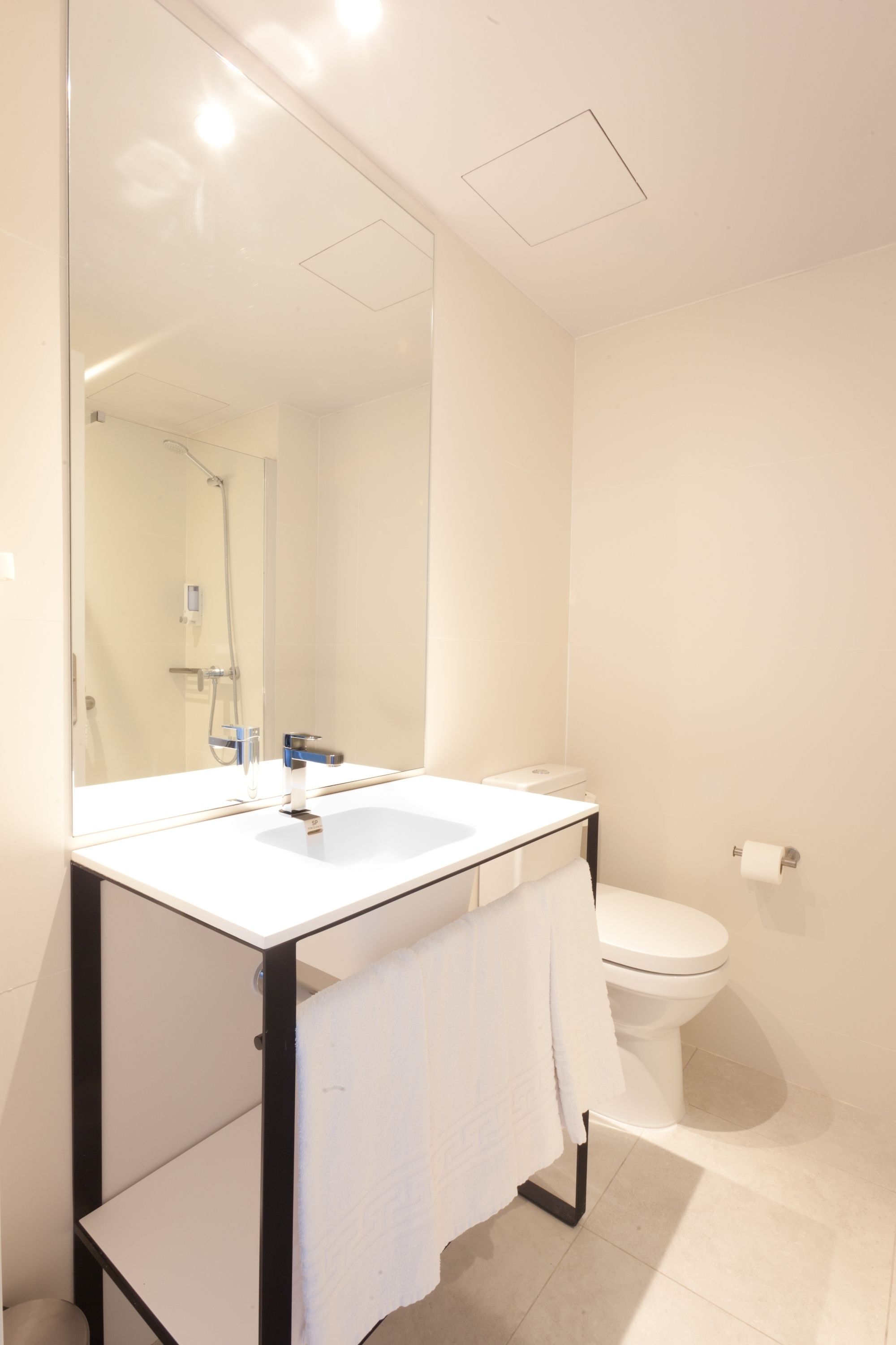 A modern bathroom with a white sink, mirror, and toilet.