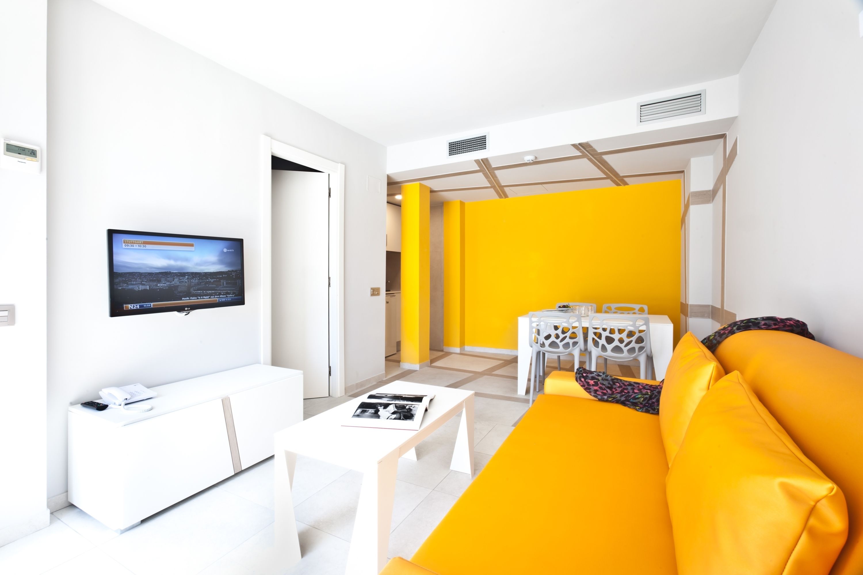 Una sala de estar moderna con un sofá blanco, una mesa de centro y un comedor con una mesa y sillas.
