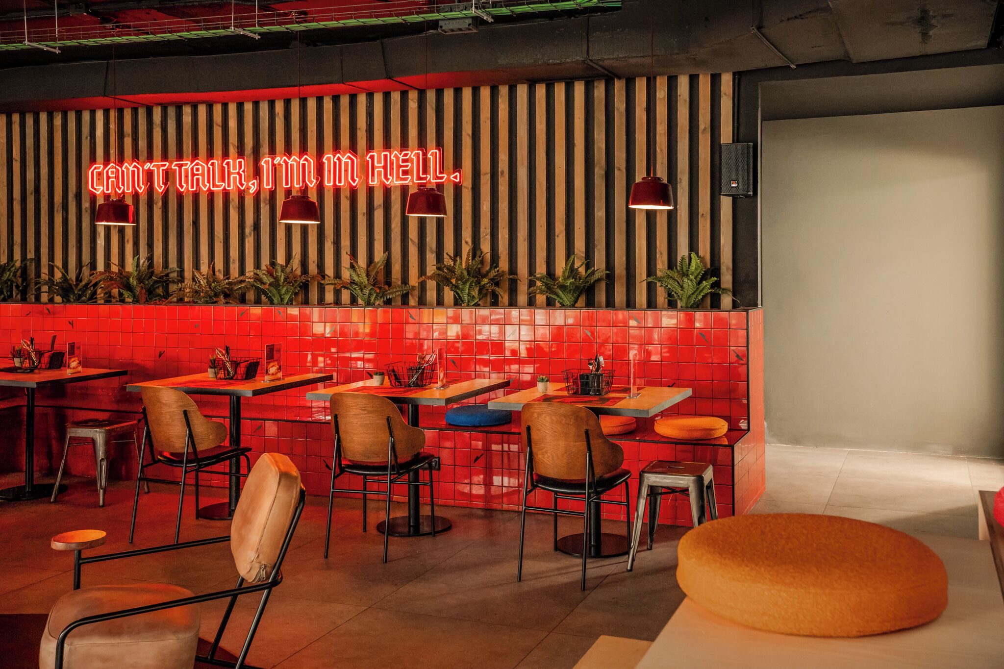 A modern restaurant interior with red and wooden decor, neon sign, and multiple seating areas.