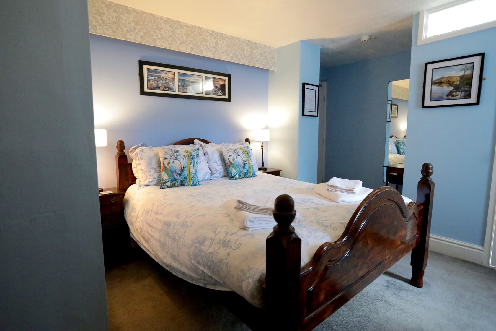 A bedroom with a large bed, two bedside lamps, and a framed picture above the bed.