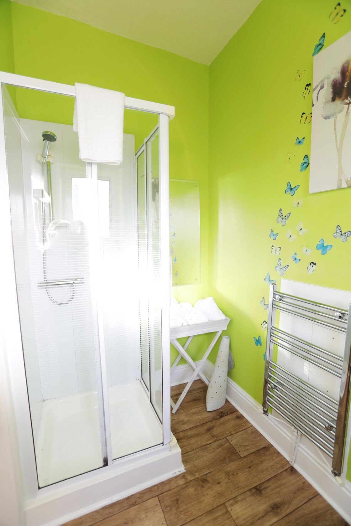 Une salle de bain avec une douche à parois de verre, un lavabo blanc et un porte-serviettes.