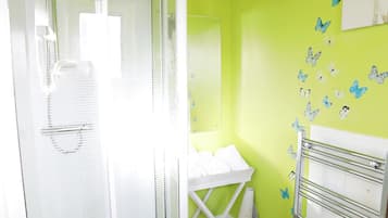 Une salle de bain avec une douche à parois de verre, un lavabo blanc et un porte-serviettes.