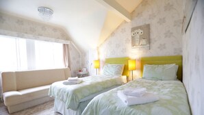 A hotel room with two beds, a sofa, a lamp, and a painting on the wall. - Bryn Woodlands House (Colwyn Bay)