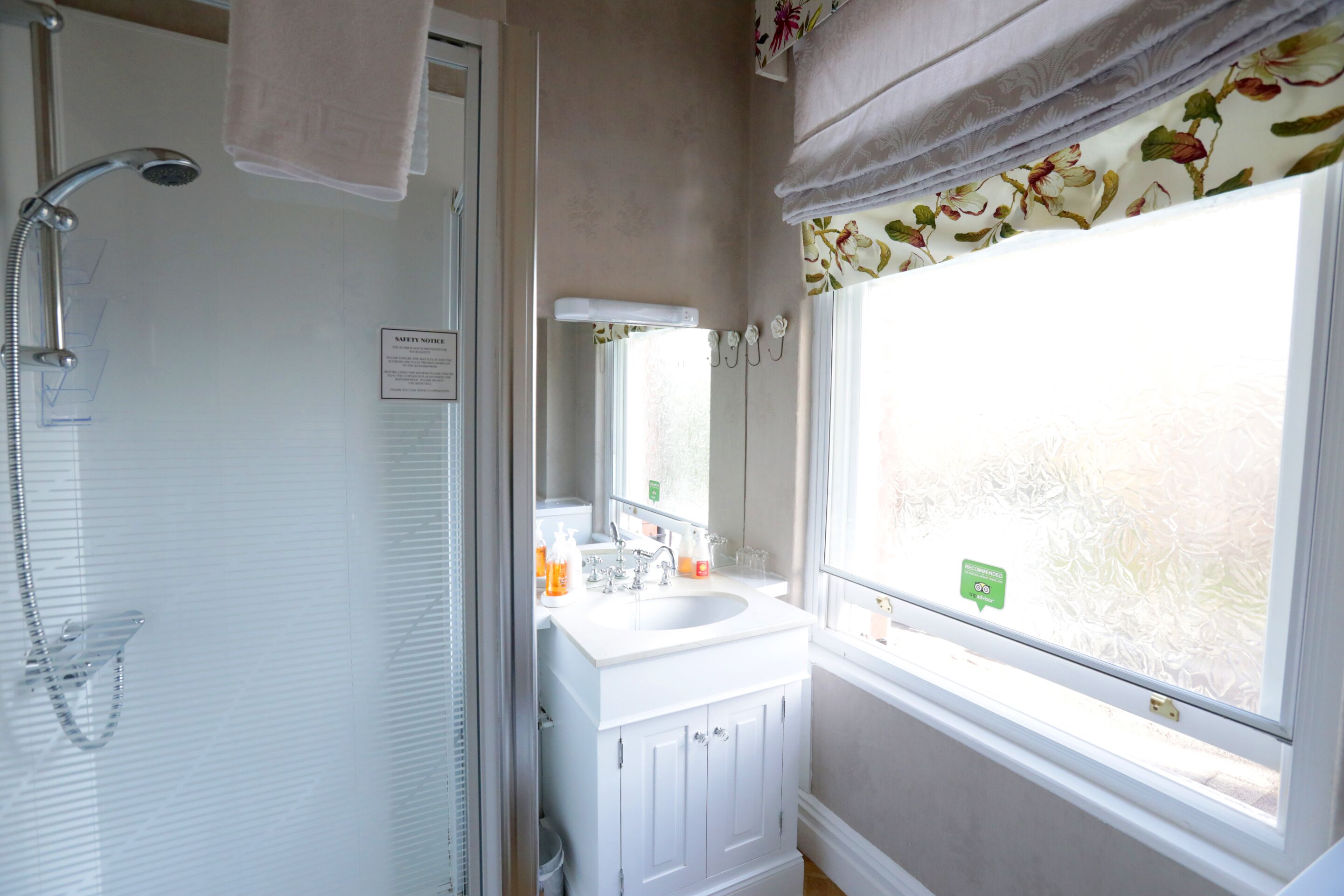 A bathroom with a shower, sink, and window.