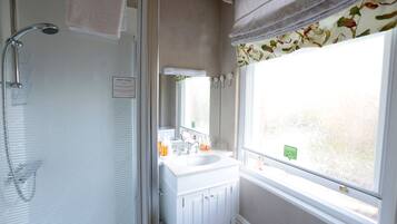 A bathroom with a shower, sink, and window.