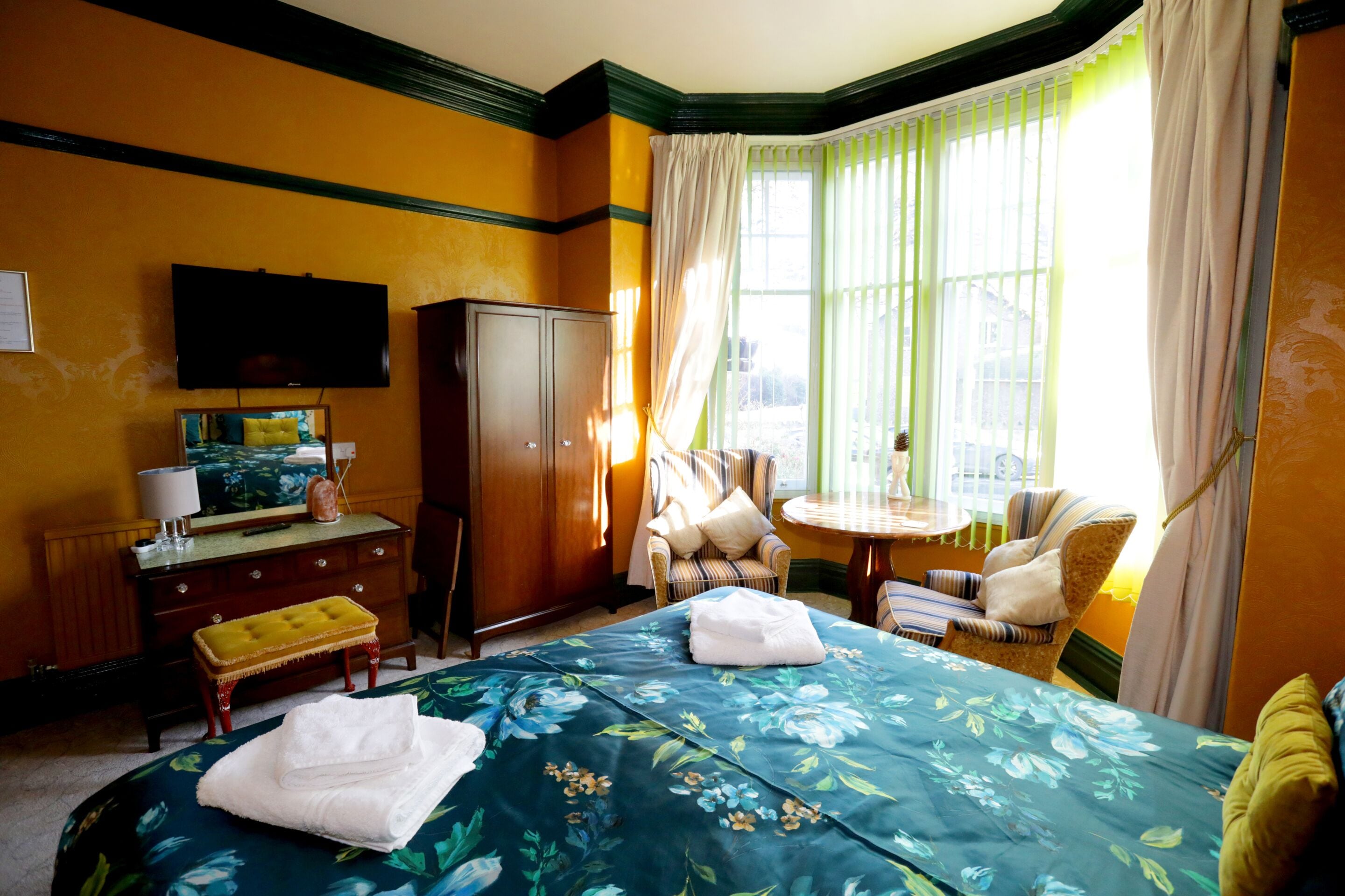 A hotel room with a bed, a desk, a television, and a window with curtains.