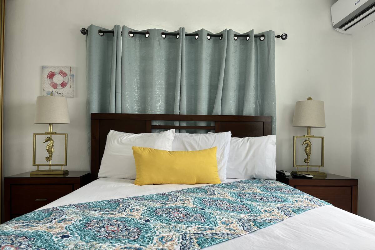 A neatly made bed with a patterned bedspread, two bedside lamps, and a headboard.