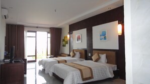 Habitación de hotel con dos camas, un escritorio y un ventanal grande.
