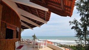 Un restaurante en la playa con terraza al aire libre y vistas al océano.