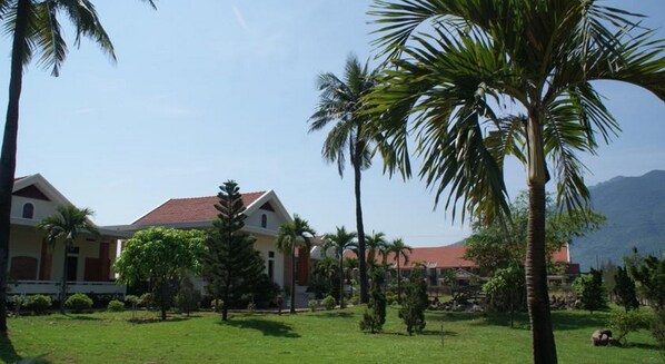 Resort com vários edifícios, palmeiras e montanhas ao fundo.