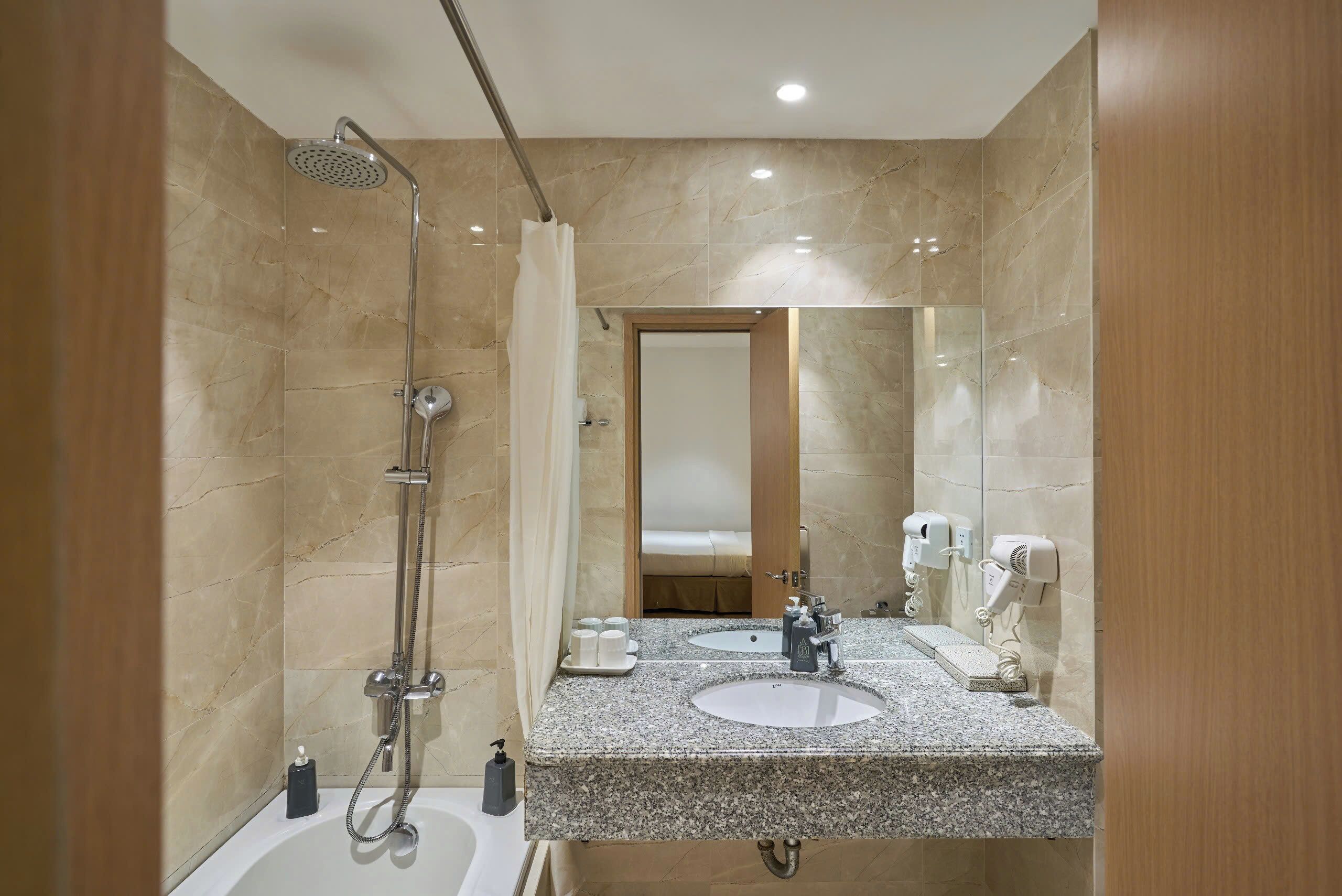 A modern bathroom with a shower, two sinks, a mirror, and a toilet.
