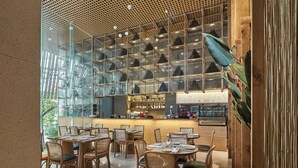 A restaurant with a bar area, wooden furniture, and a glass display case with items. -  Sky Gem Hotel Sora (Ho Chi Minh City)