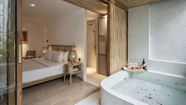 A bedroom with a large bed, bedside lamps, a wooden nightstand, and a shower area. -  Sky Gem Hotel Sora (Ho Chi Minh City)