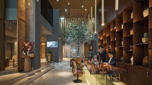 A modern lobby with a reception desk, seating area, and a large tree. -  Sky Gem Hotel Sora (Ho Chi Minh City)