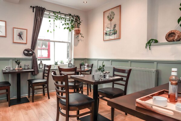 A cozy dining area with wooden tables and chairs, a window with curtains, and wall-mounted decor. - The Endeavour Restaurant With Rooms (Saltburn-by-the-Sea)
