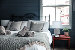 A neatly made bed with rolled towels, a bedside lamp, and a small table with a plant and book. - The Endeavour Restaurant With Rooms (Saltburn-by-the-Sea)