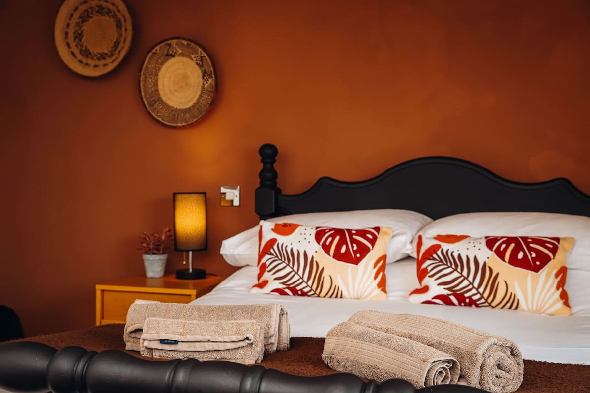 A neatly made bed with two pillows, a bedside lamp, and two wall-mounted decorative plates.