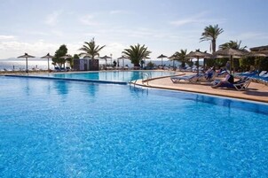 Una piscina al aire libre, sillones reclinables de piscina