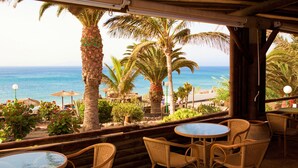 A beachside patio with wicker furniture and a view of the ocean. - Monéa Royal Mónica (Yaiza)