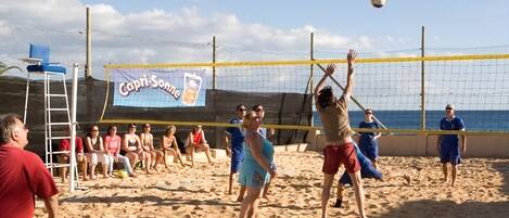 Un match de volleyball de plage avec des joueurs et des spectateurs sur un terrain de sable.
