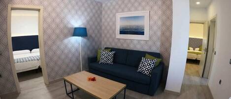 A compact living space with a bed, a sofa, a coffee table, and a lamp.