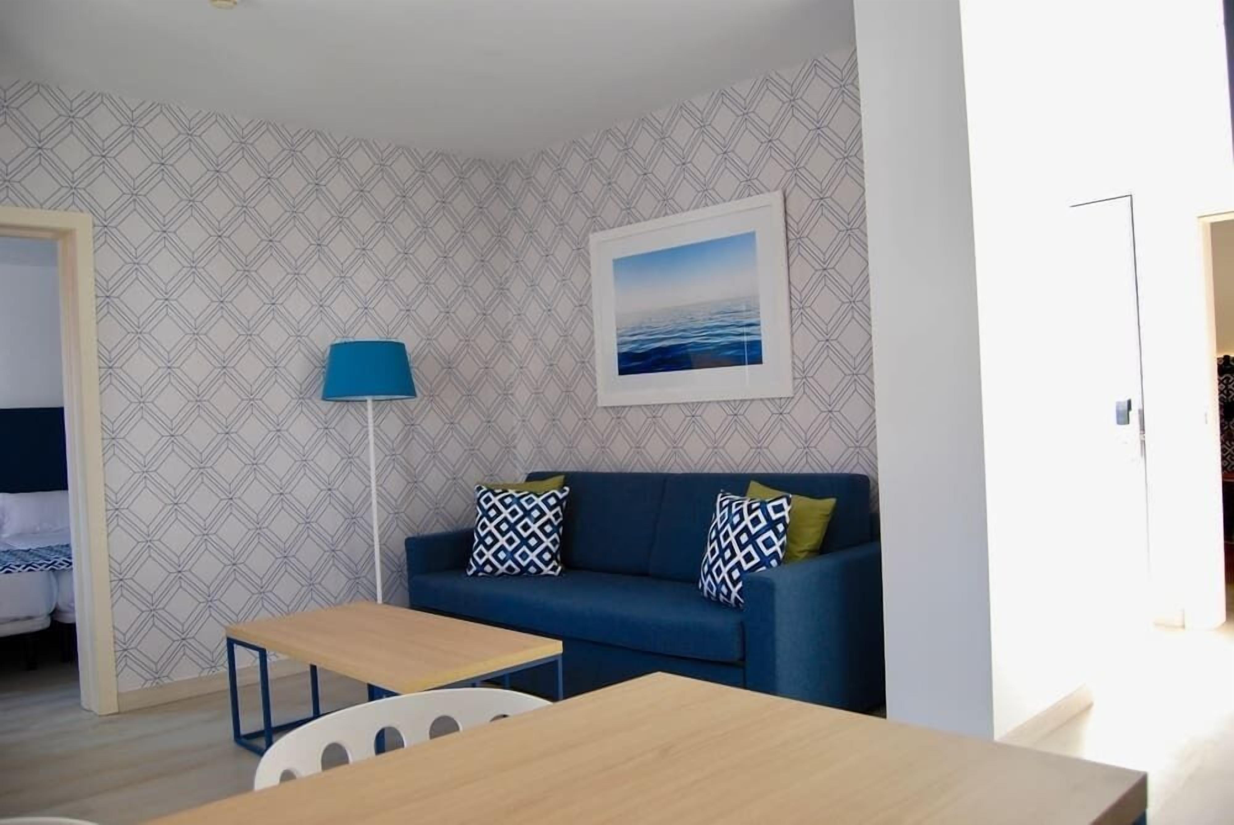 A modern room with a blue sofa, a small wooden table, and a floor lamp.