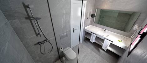 A modern bathroom with a glass-enclosed shower, a white sink, and a large mirror.