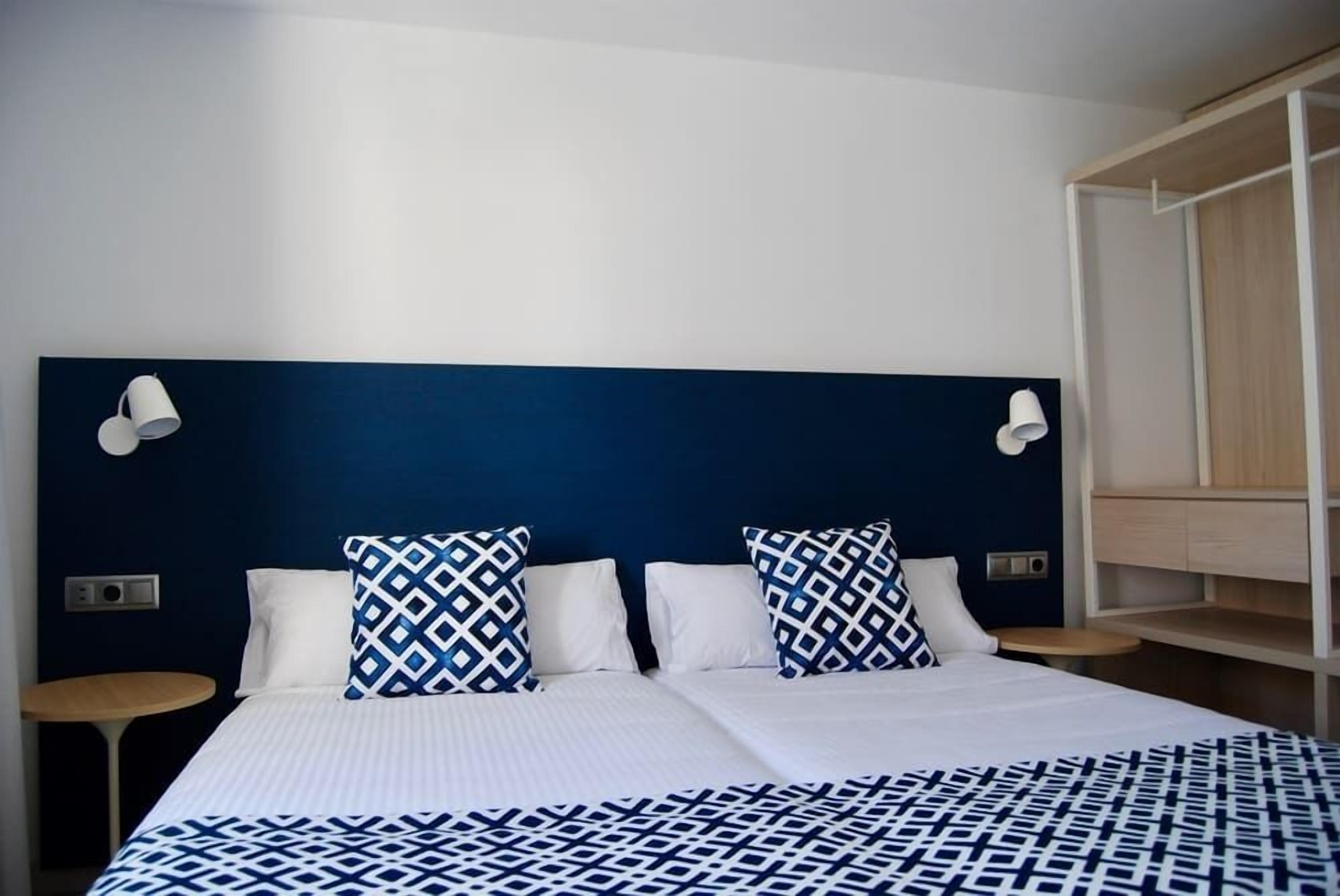 Una habitación de hotel con una cama grande, dos mesitas de noche y un armario.