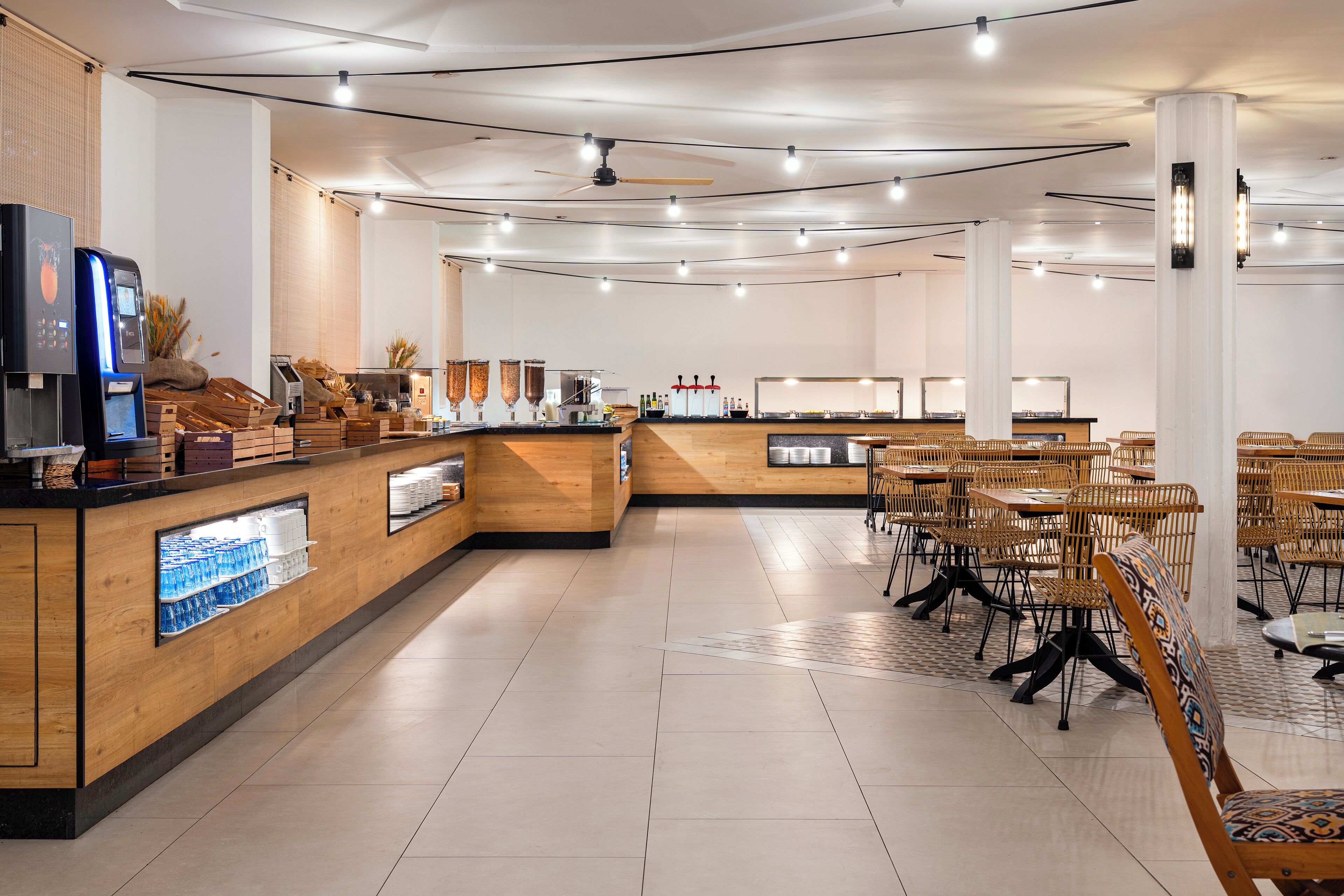 Un café moderno con mostrador de madera, zona de estar y ventiladores de techo.