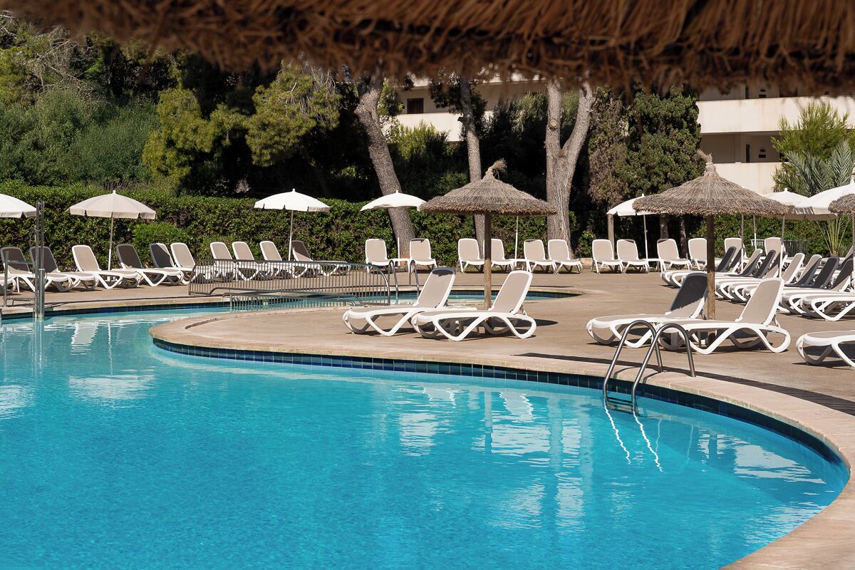 A pool area with lounge chairs and umbrellas.