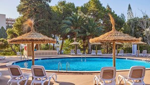 A swimming pool with lounge chairs and thatched umbrellas. - tent Palmanova (Calvia)