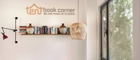 A cozy reading nook with a bookshelf, a hanging light, and a window with a view of trees.