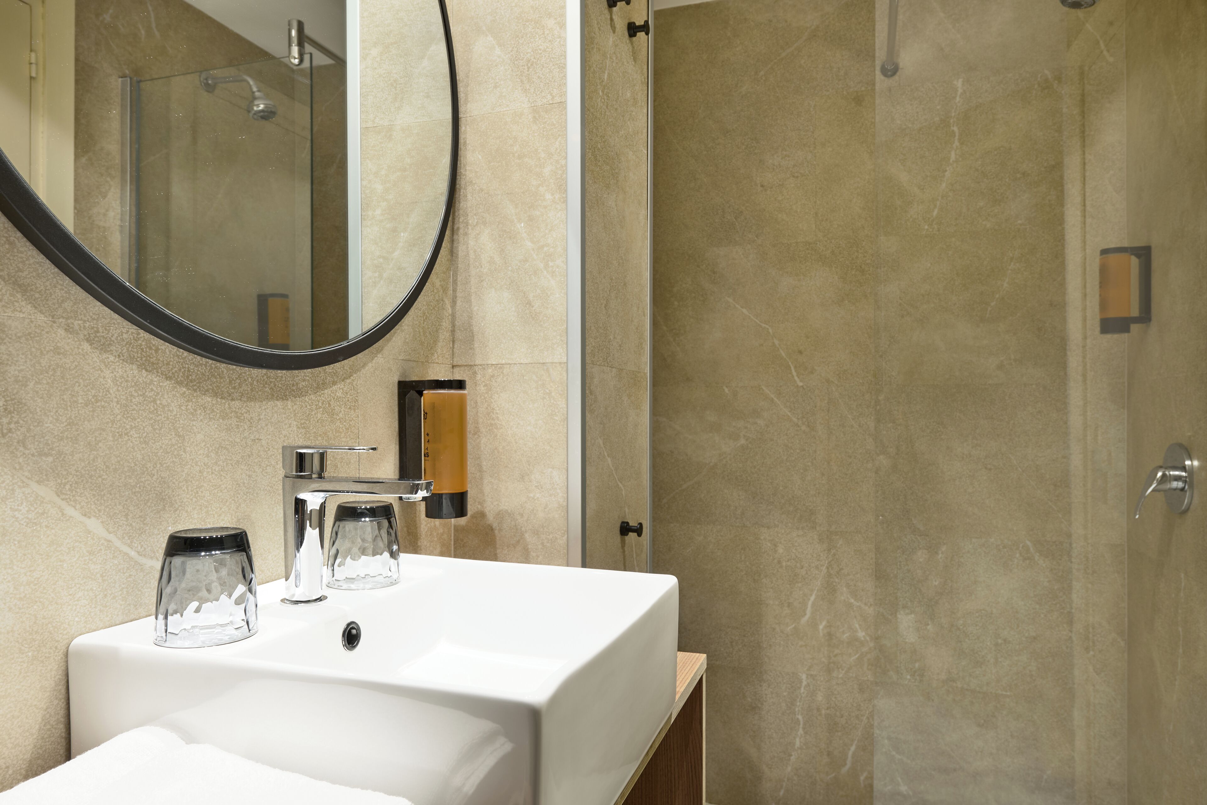 A bathroom with a white sink, a mirror, and a shower area.