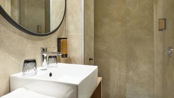 A bathroom with a white sink, a mirror, and a shower area.