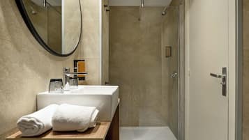 Un baño moderno con un espejo grande, un lavabo y una ducha.